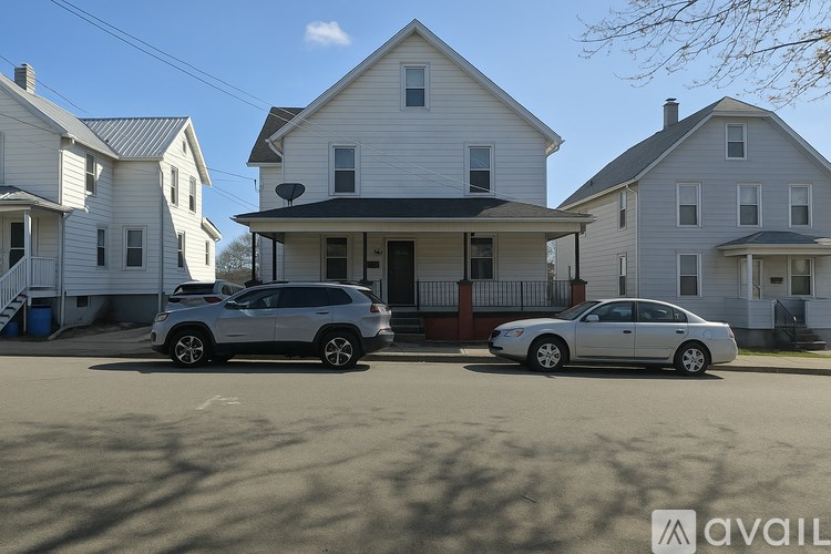 Two cars are parked in front of a white house.