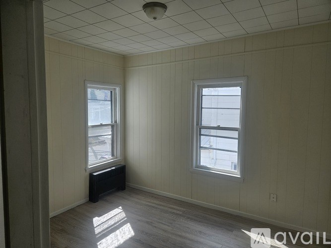 A room with two windows and a bench in the corner.