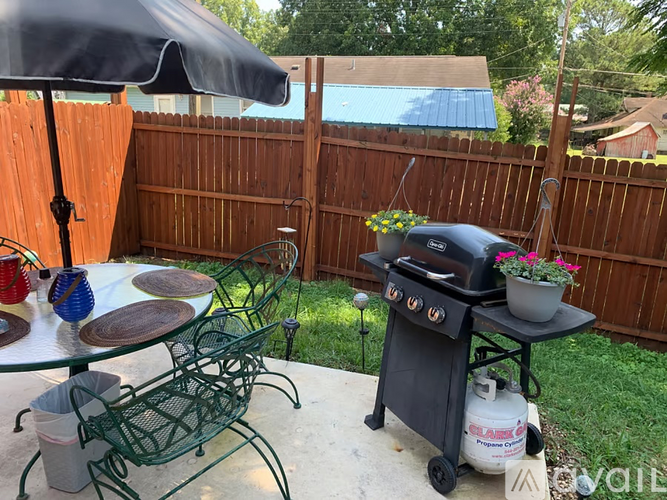 A black grill is on a patio table with a green chair.