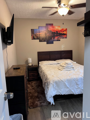 A bedroom with a bed, dresser, and a ceiling fan.