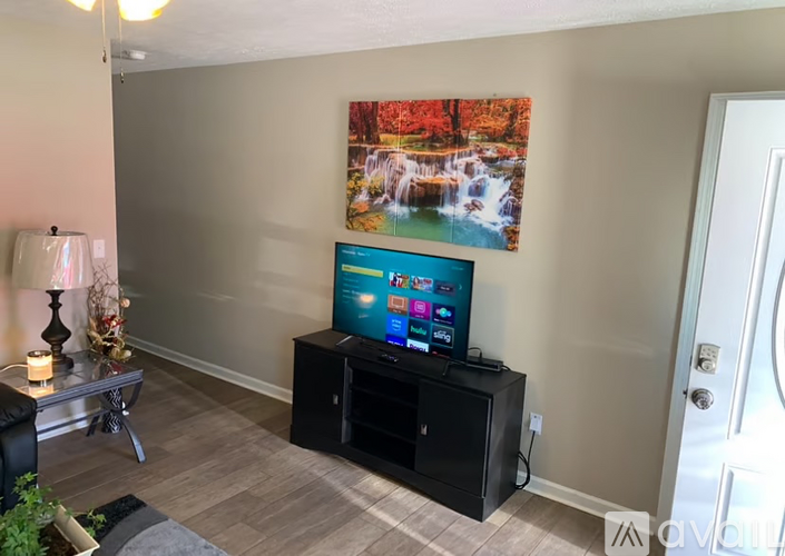 A living room with a television and a painting of a waterfall on the wall.