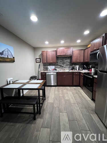 A kitchen with a table and chairs in front of a stainless steel refrigerator.