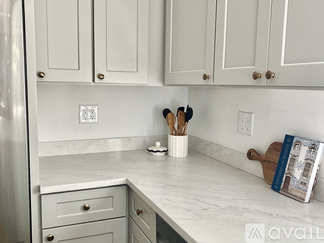 A kitchen with white cabinets and a marble countertop.