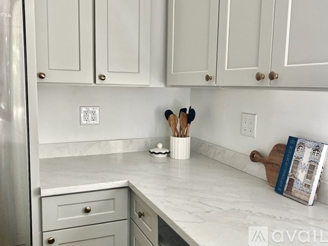 A kitchen with white cabinets and a marble countertop.