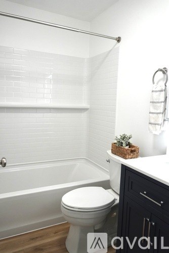 A white toilet in a bathroom with a white tub and a white towel rack.