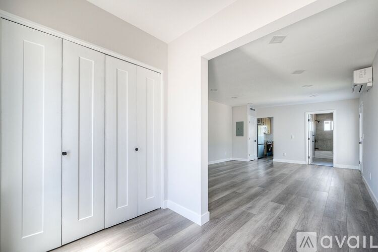 A spacious room with white walls and a wooden floor.