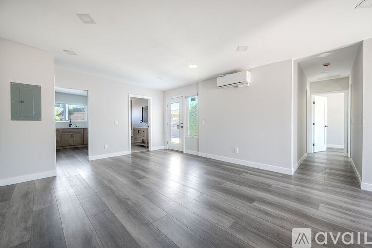 A spacious room with wood flooring and white walls.