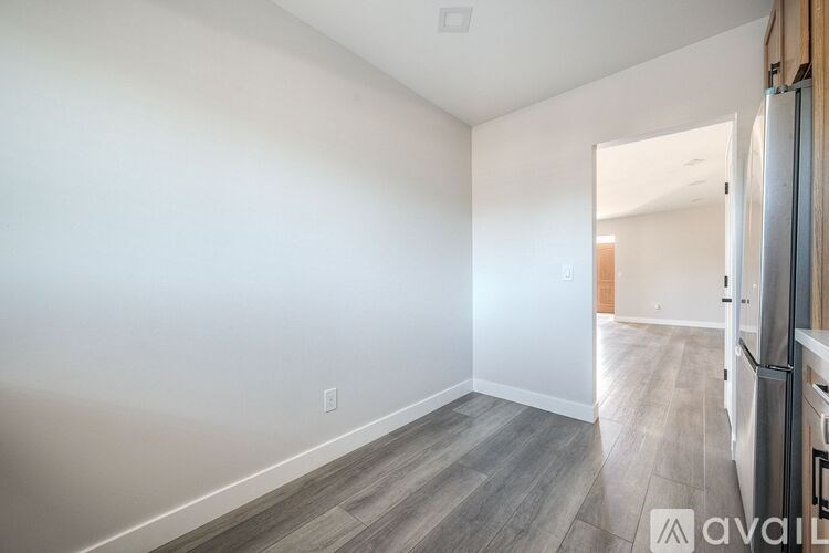 A spacious room with a wooden floor and white walls.