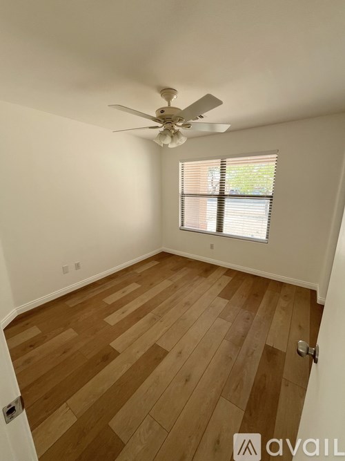 A room with wooden flooring and a ceiling fan.
