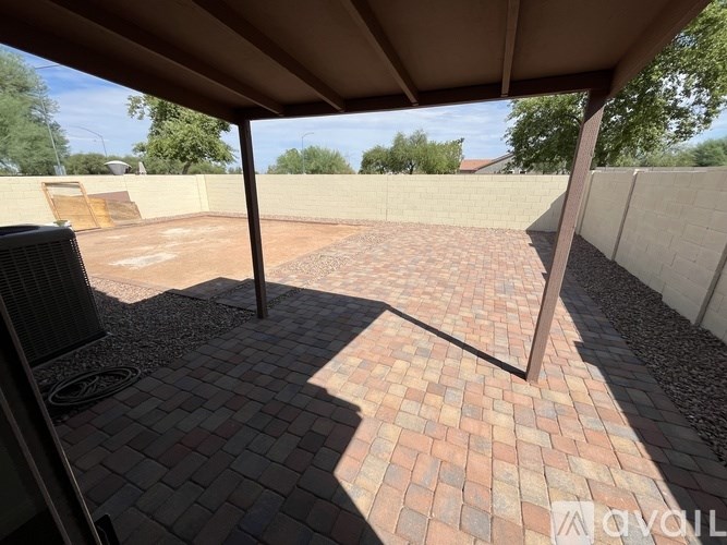 A patio with a brick floor and a white wall.