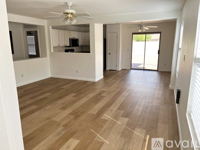 A spacious room with wooden flooring and a ceiling fan.