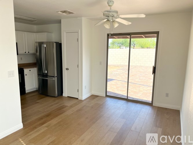 A kitchen with a refrigerator, cabinets, and a ceiling fan.