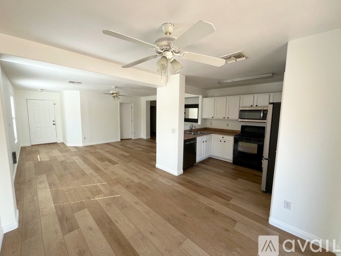 A spacious kitchen and living room with wooden flooring and white walls.