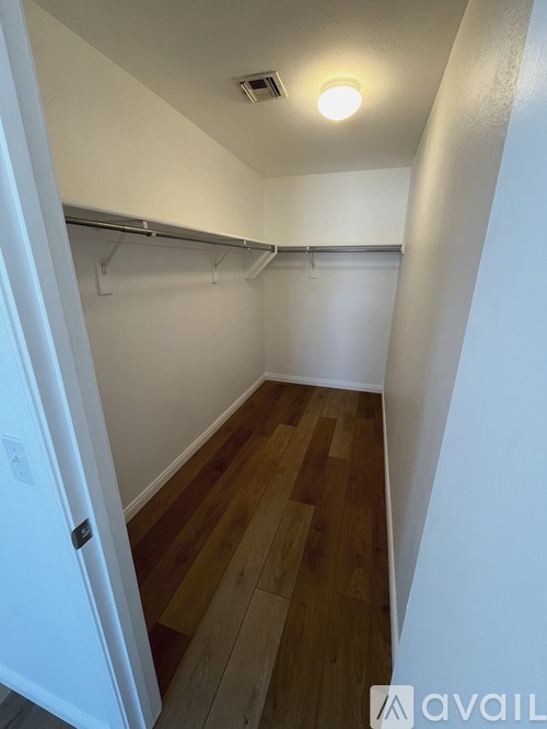 A small, empty room with wooden floors and white walls.