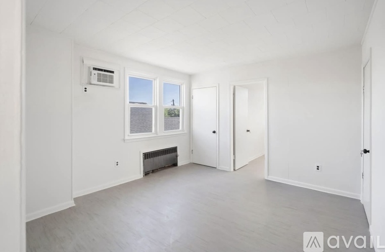 A spacious room with a fireplace and a window overlooking a tree.