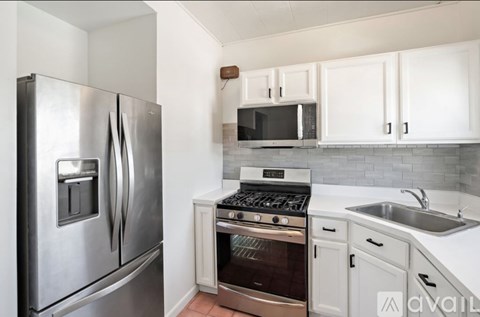A kitchen with a stainless steel refrigerator and white cabinets.