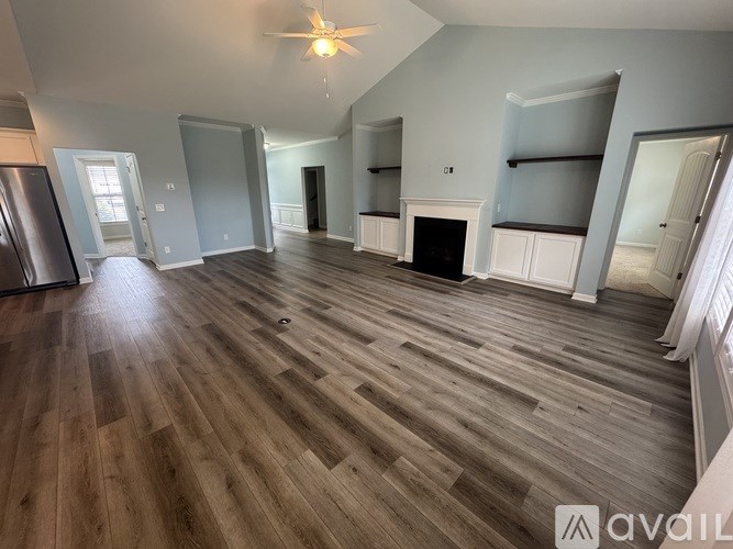A spacious living room with wood flooring and a fireplace.