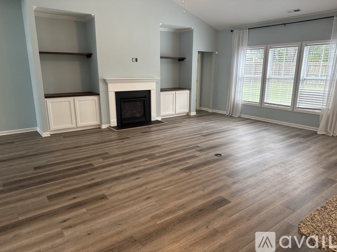 A living room with a fireplace and wooden floors.