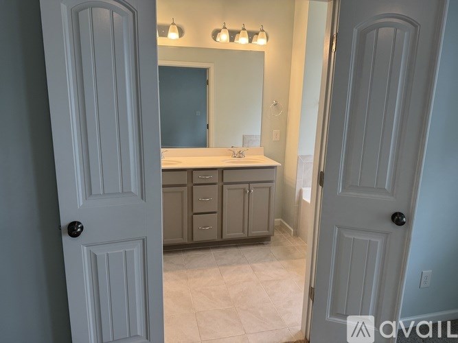 A bathroom with a vanity, mirror, and lighting fixtures.