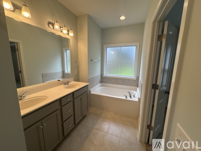 A bathroom with a tub, sink, and mirror.