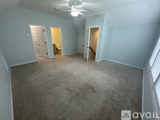A spacious room with a carpeted floor and a ceiling fan.