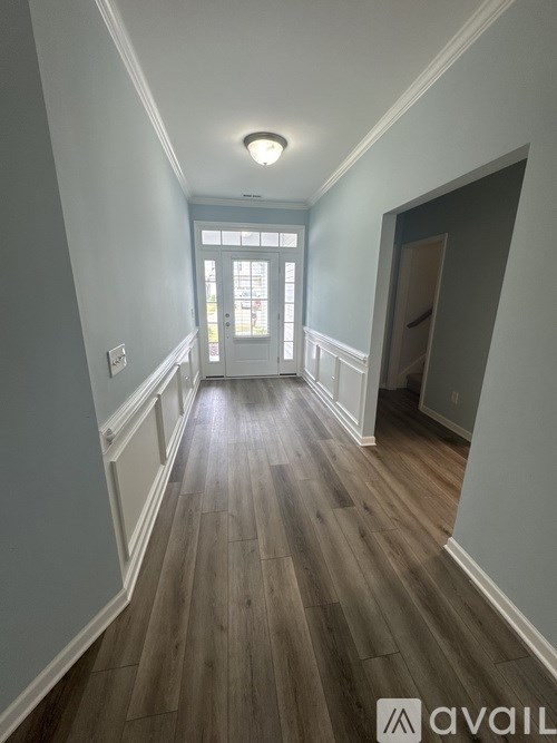 A long hallway with wood floors and white walls.