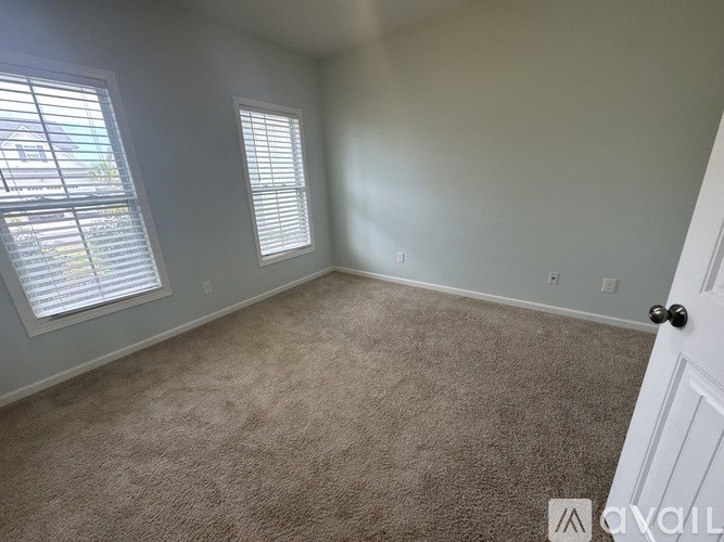 A room with a carpeted floor and a door on the right side.