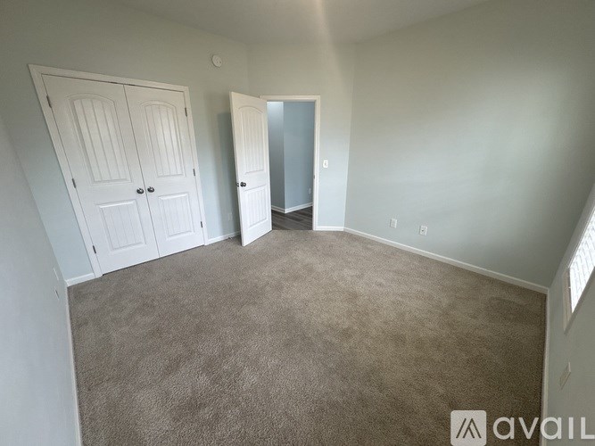 A room with a carpeted floor and two doors.