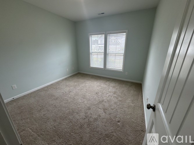 A room with a carpeted floor and a window with blinds.