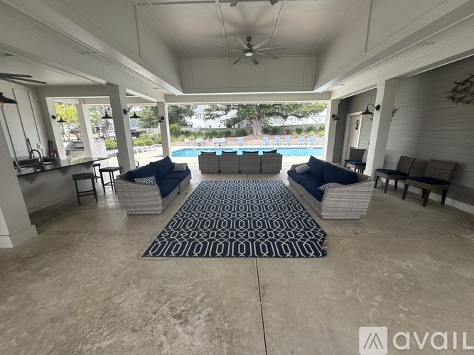 A patio with a pool in the background and a rug on the floor.