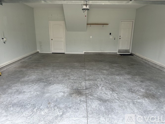 A large empty room with concrete flooring and white walls.