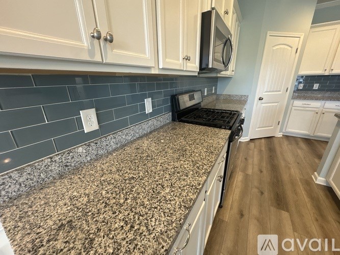 A kitchen with granite countertops and white cabinets.