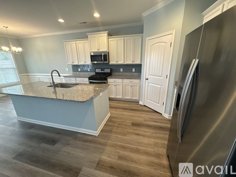 A kitchen with a stainless steel refrigerator and wooden flooring.