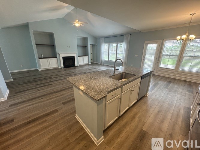 A spacious kitchen with a granite countertop and wooden flooring.