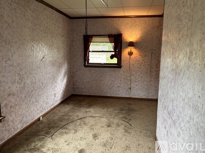 A room with a window and a lamp on the wall.