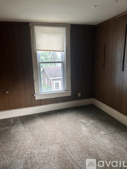 A room with a window and a carpeted floor.