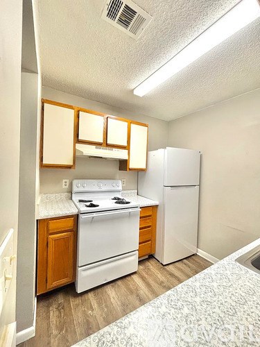 A small kitchen with a white stove and a white refrigerator.