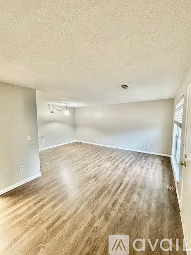 A room with wooden flooring and white walls.