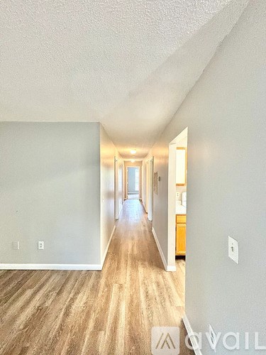 A long hallway with wood floors and white walls.