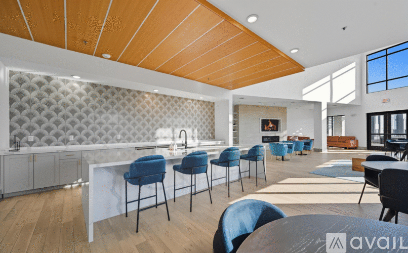 A modern kitchen with blue chairs and a wooden ceiling.