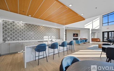 A modern kitchen with blue chairs and a wooden ceiling.