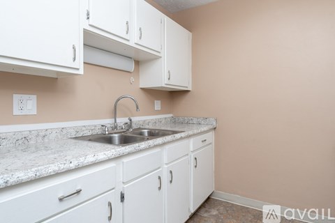 A kitchen with white cabinets and a marble countertop.