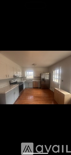 A kitchen with white cabinets and a wooden floor.