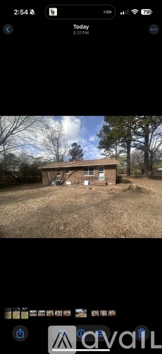 A small house with a brown roof is surrounded by trees.