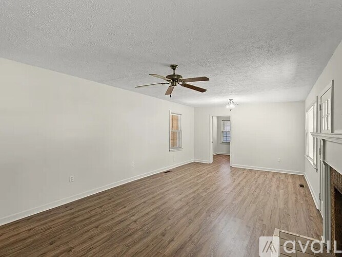 A room with wooden floors and two windows.