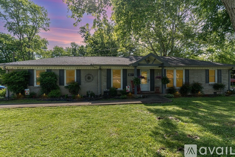 A house with a front yard and a tree in front of it.