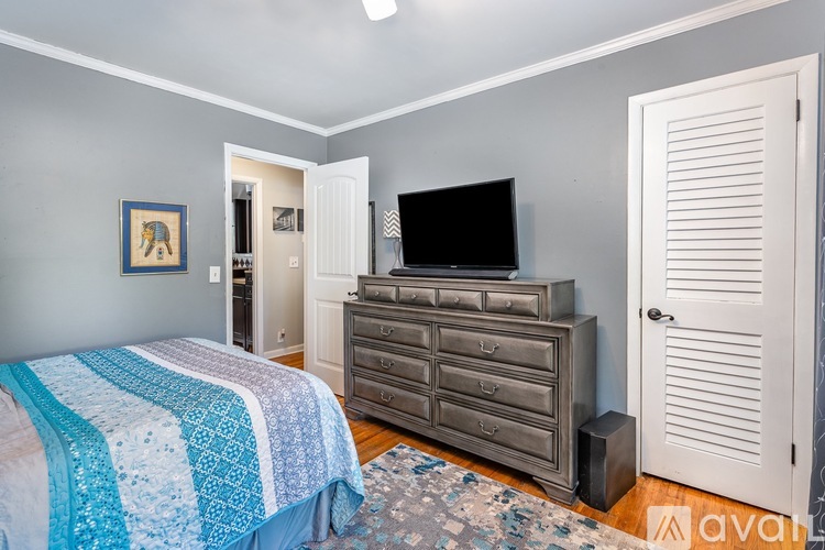 A bedroom with a bed, dresser, and television.