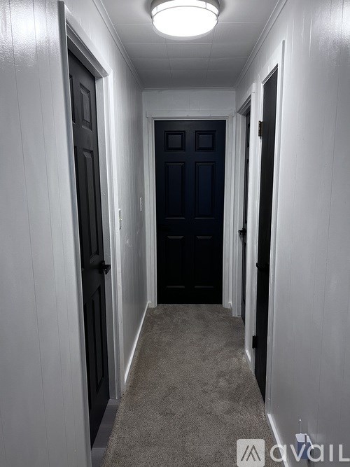 A hallway with a carpeted floor and white walls.