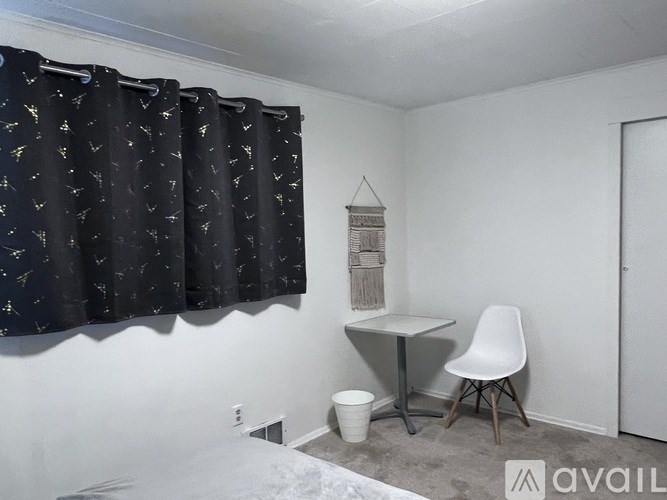 A room with a desk and chair and a window with curtains.