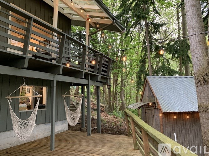 A wooden deck with hammocks and a small cabin in the woods.